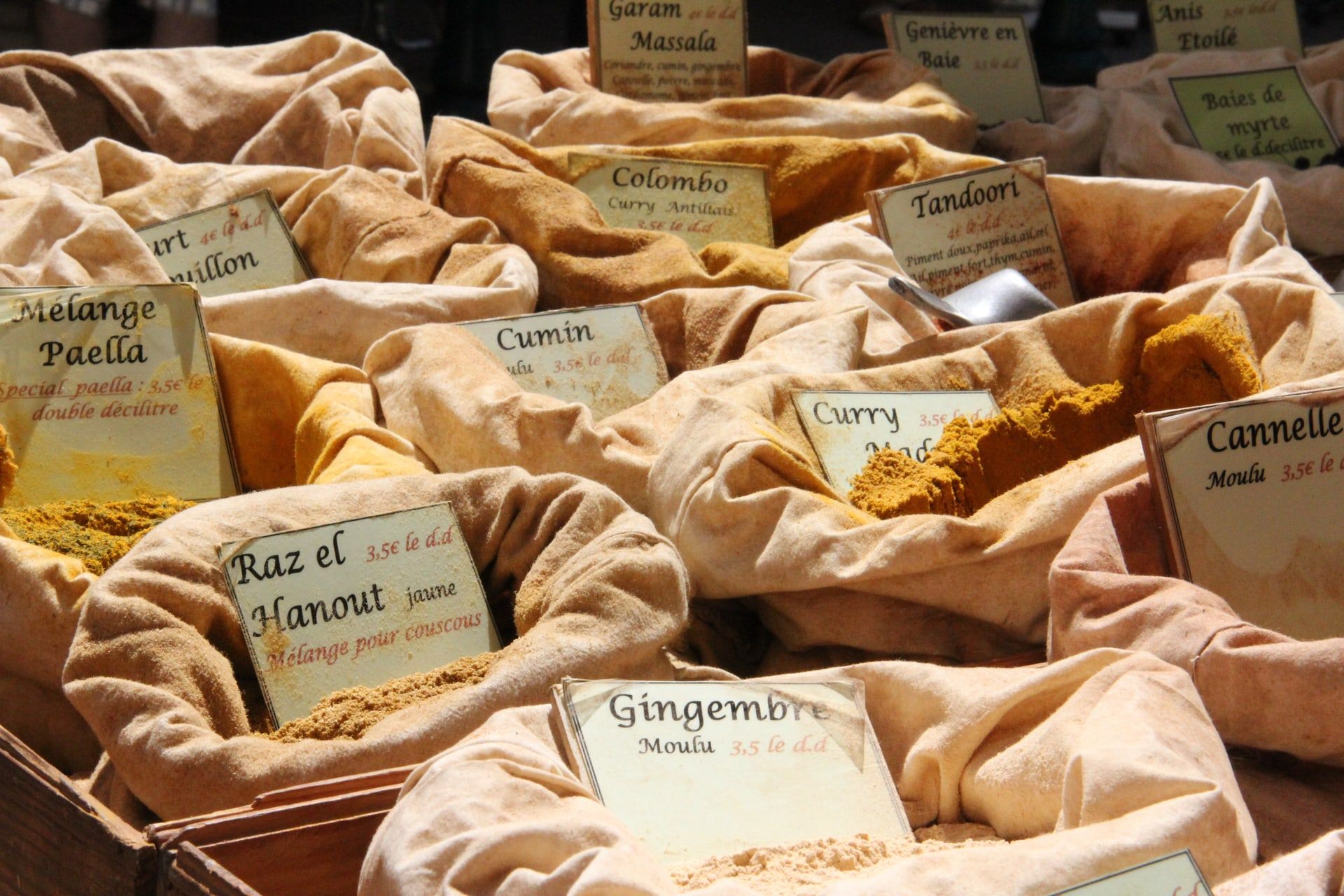 Gewürzstand auf einem korsischen Wochenmarkt mit Currys, Paella-Mischung und Ras el Hanout in Leinensäcken