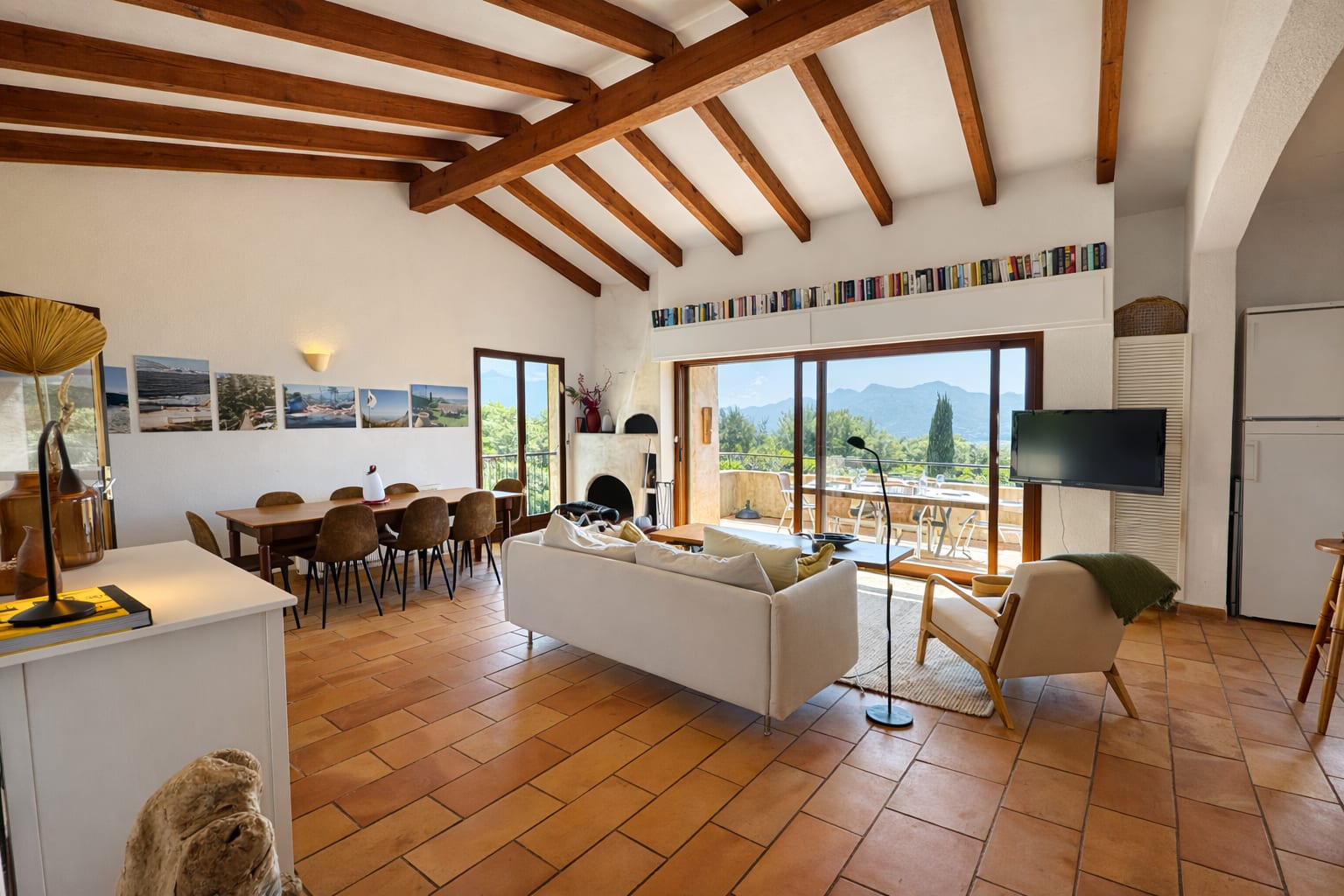 Offener Wohn- und Essbereich der Casa di Lumi mit langem Esstisch, Sofa und Bergblick durch die Glasfront